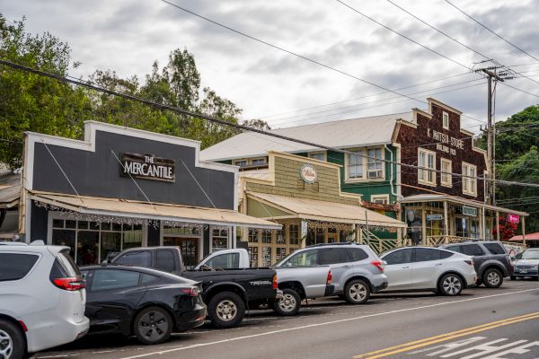 A street scene with parked cars in front of several buildings, including one with "The Mercantile" sign on it, under a cloudy sky.