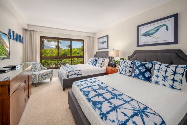 A cozy bedroom with two double beds, ocean-themed decor, a scenic window view, and tropical-style furnishings.