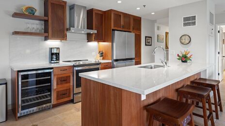 A modern kitchen with wooden cabinets, island with stools, stainless steel appliances, and bright lighting for a clean look.
